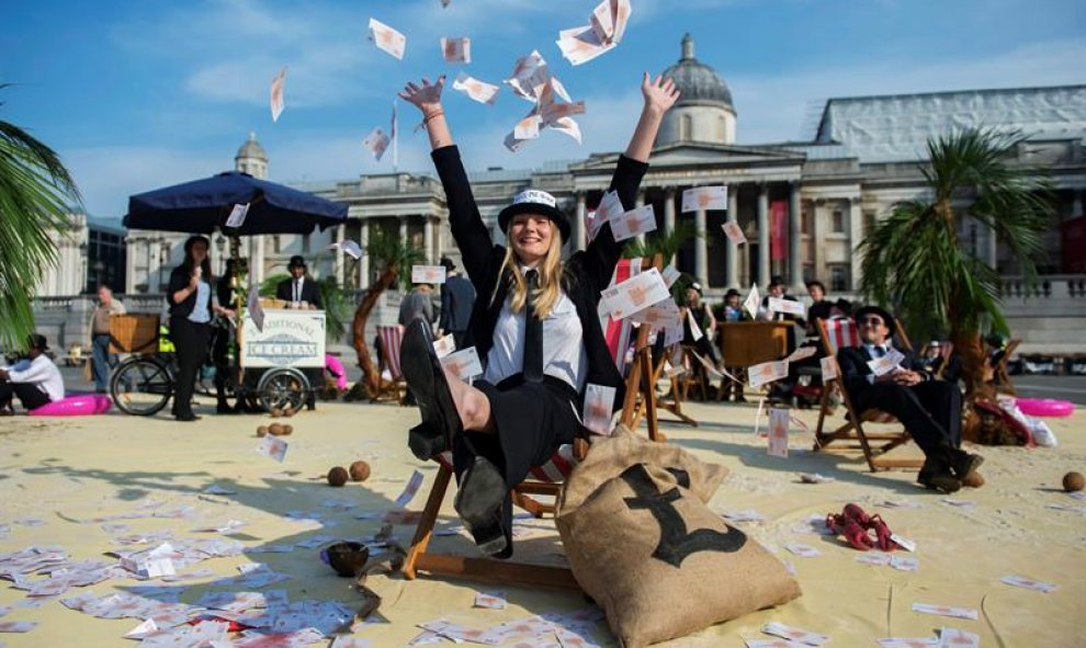 Una mujer lanza billetes al aire en una protesta contra los paraísos fiscales en la plaza Trafalgar de Londres. EFE/Hannah Mckay