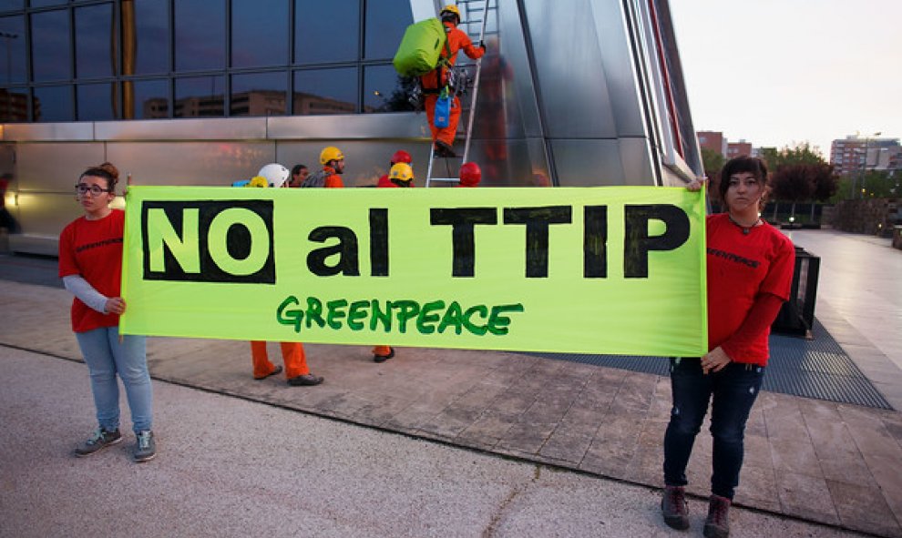 Miembros de Greenpeace muestras una pancarta en protesta contra el TTIP. GREENPEACE.