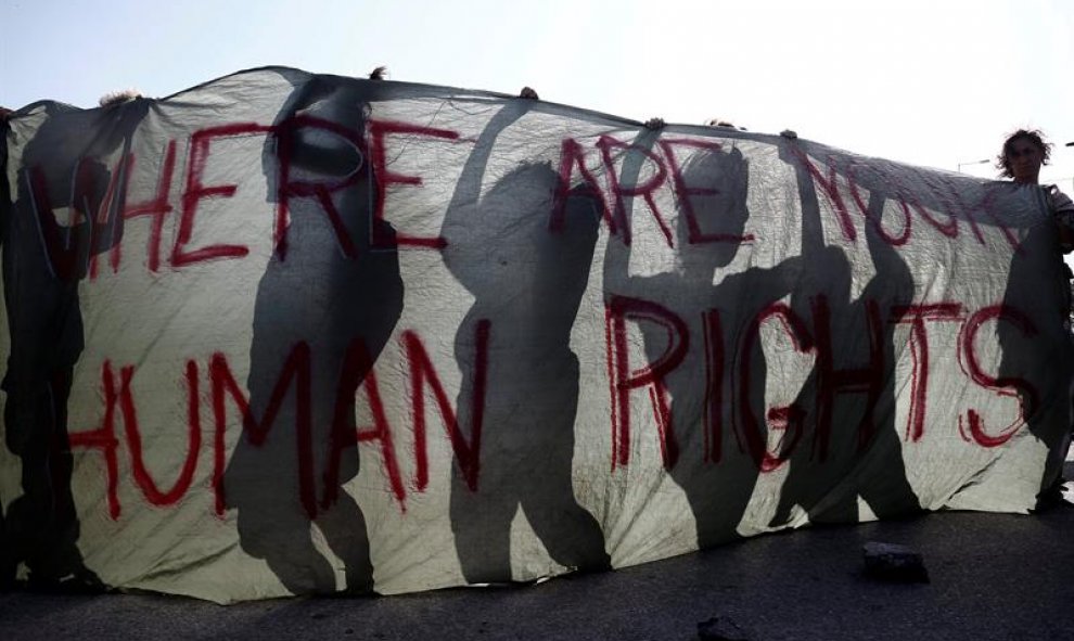 Varias personas con una pancarta en la que se lee 'Dónde están vuestros Derechos Humanos' participan en una manifestación en solidaridad con los refugiados de Idomeni, junto al campo de refugiados de dicha localidad griega tras el desalojo del campamento,