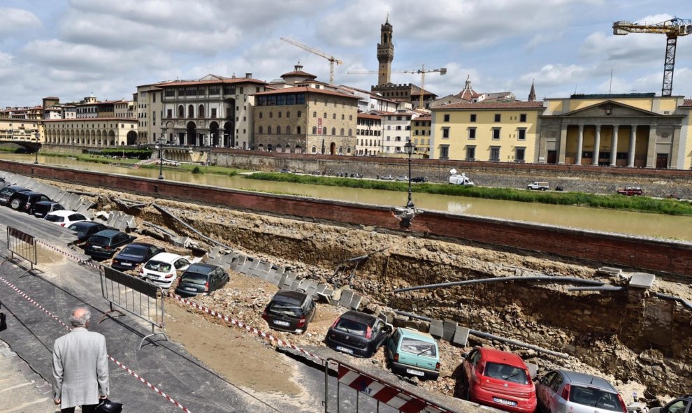 Un viandante observa los vehículos engullidos por un socavón cerca del famoso Puente Viejo a orillas del río Arno, en el centro de la ciudad italiana de Florencia (Italia). EFE/Maurizio Degl' Innocenti