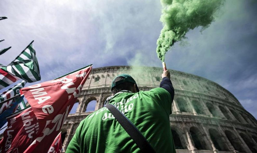 Un manifestante sujeta una bengala de humo frente al Coliseo de Roma durante una protesta convocada por los sindicatos coincidiendo con la huelga de empleados públicos, en Roma, Italia. EFE/Angelo Carconi