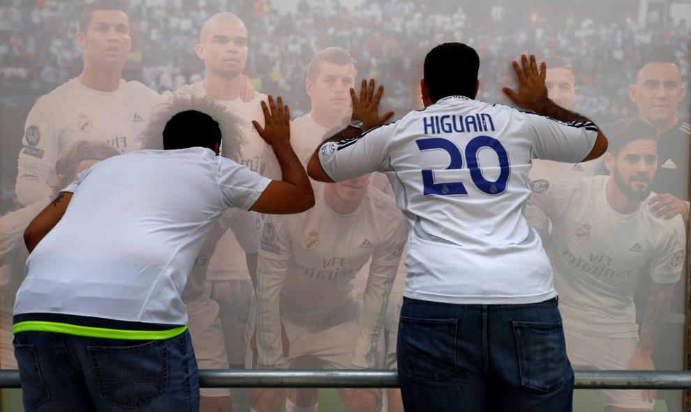 Dos aficionados posan para una foto con un poster de los jugadores del Real Madrid en Milán, donde el sábado se juega la fina de la Champions League. REUTERS/Pawel Kopczynski