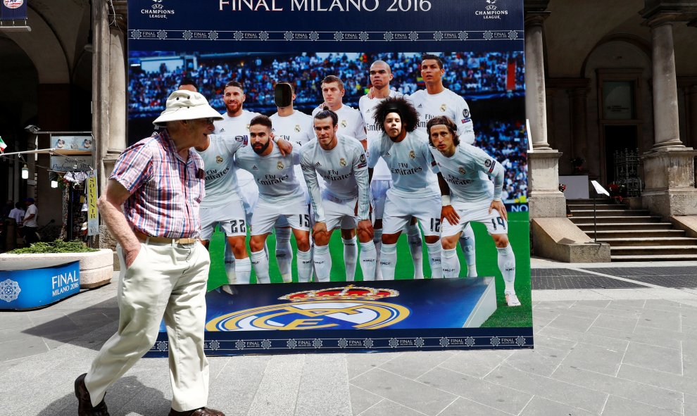 Un hombre pasea por la Piazza dei Duomo, junto a un poster de los jugadores del Real Madrid, para que los aficionados se hagan fotos. REUTERS/Pawel Kopczynski