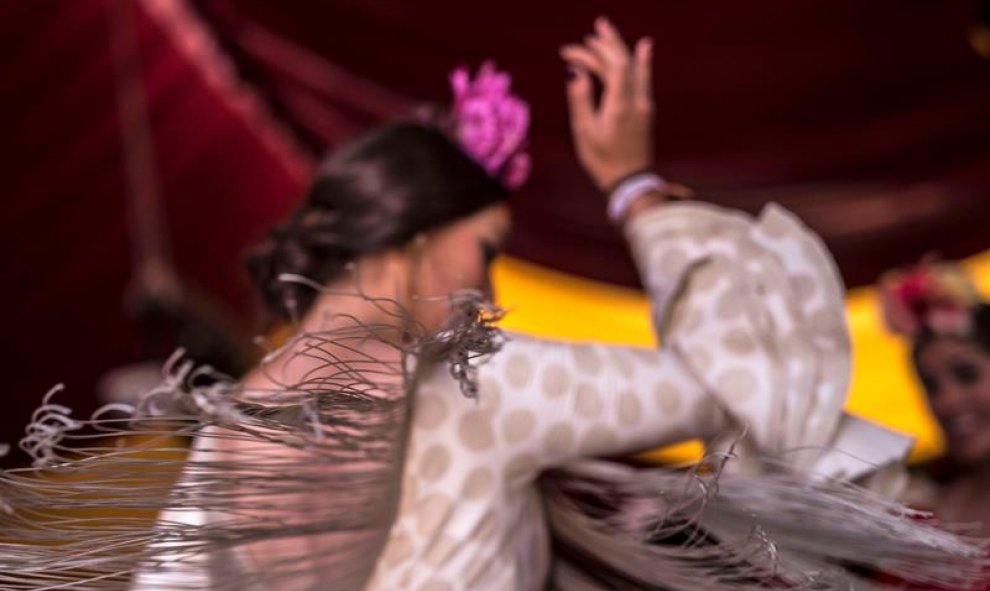 Una joven vestida de flamenca baila durante la Feria de Córdoba. EFE/Rafa Alcaide