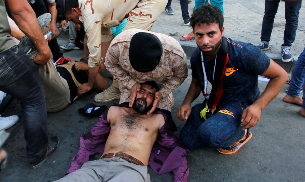 Manifestantes afectados por  gas lacrimógeno en el suelo después de que tratasen de de acercarse a la Zona Verde fortificada en la plaza Tahrir de Bagdad , Irak.- REUTERS / Jalid al Mousily