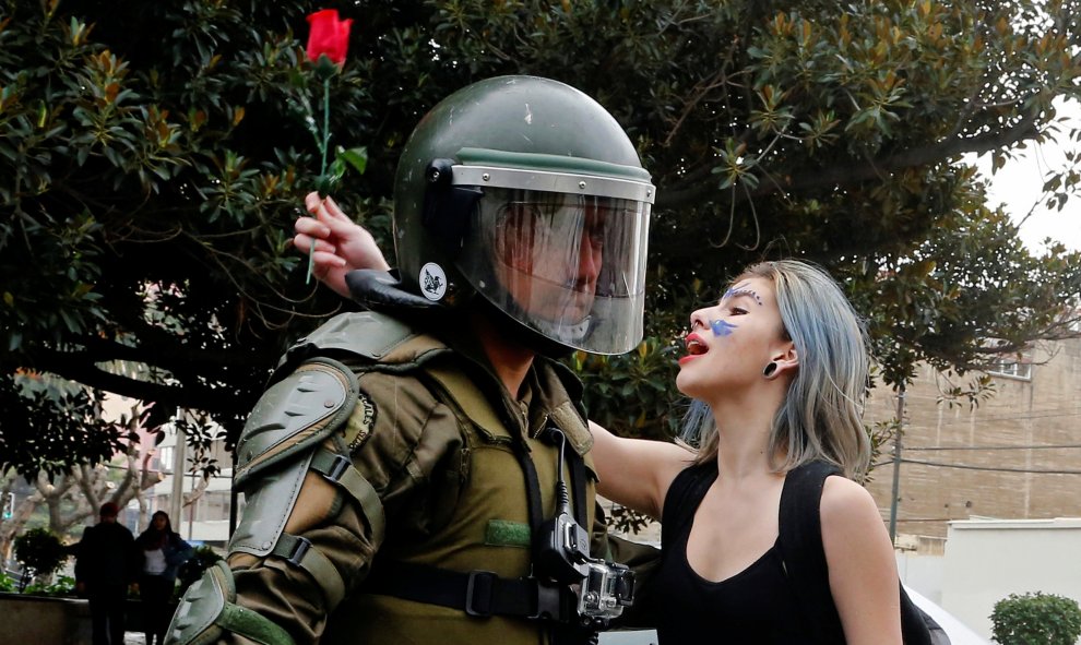 Un manifestante sostiene una rosa y grita consignas en frente de un policía antidisturbios durante una marcha no autorizada convocada por los estudiantes de secundaria para protestar contra las reformas educativas del gobierno en Valparaiso , Chile.- REUT