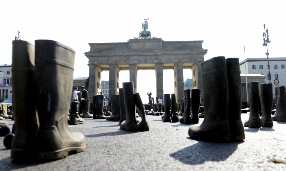 Activistas de la Federación de Ganaderos Alemanes (BDM) protestan rodeados de botas de goma en una manifestación contra el precio de la leche en la Puerta de Brandeburgo en Berlín, Alemania. EFE/Maurizio Gambarini