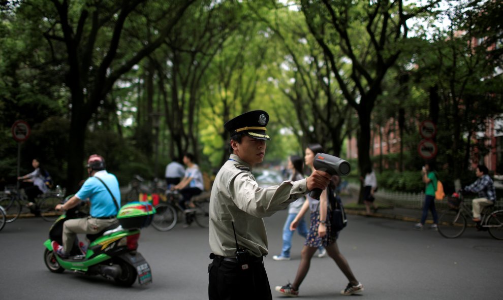 Un guardia de seguridad inspecciona la velocidad de las bicicletas eléctricas en la Universidad de Shanghai, China. REUTERS/Aly Song
