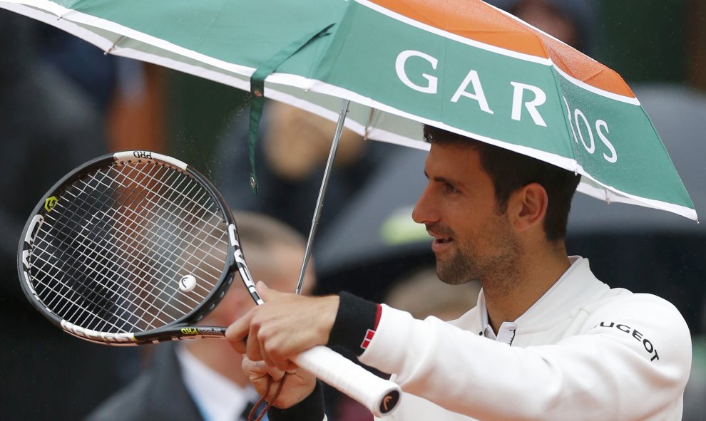 Novak Djokovic se refugia de la lluvia bajo un paraguas durante su partido contra Roberto Bautista en Roland Garros. REUTERS/Gonzalo