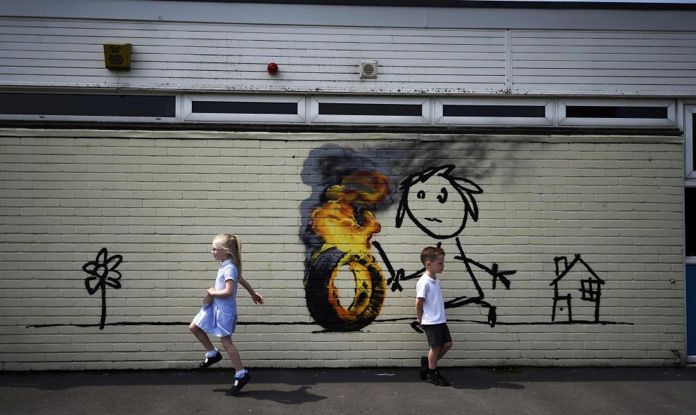 Niños frente a un graffiti del artista Banksy pintado en el exterior de un aula de la Escuela Primaria Bridge Farm en Bristol, Reino Unido.  REUTERS/Dylan Martinez