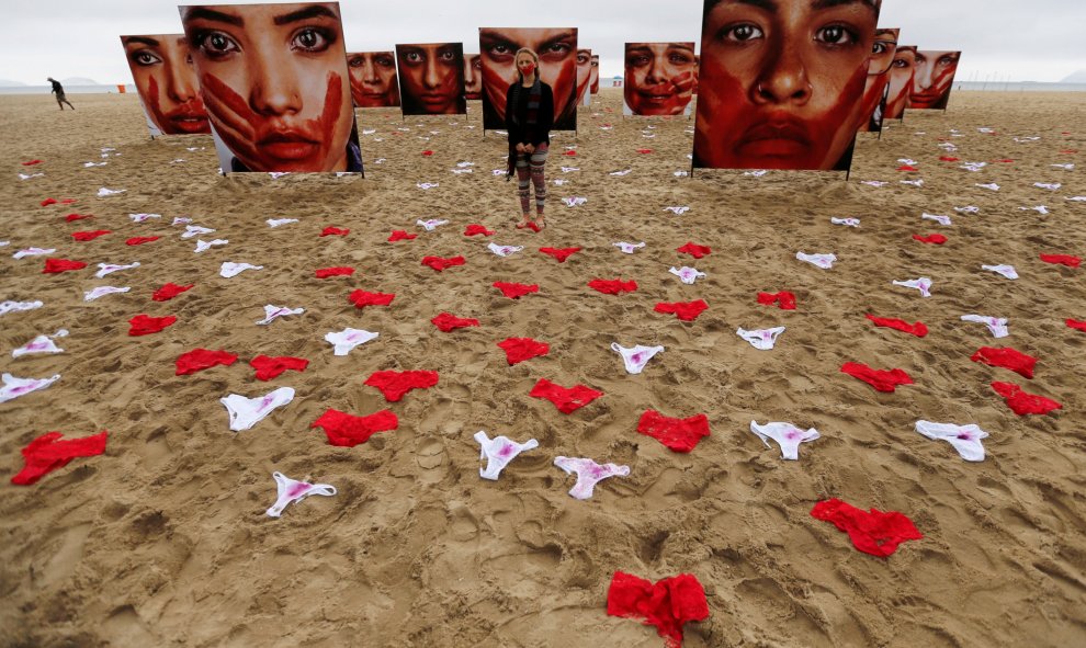 Un activista posa para la fotografía, entre ropa interior de mujeres y fotografías de Marcio Freitas durante una protesta de la ONG  Rio de Paz (Rio of Peace) contra la violencia y violación de mujeres, en la playa de Copacabana en Rio de Janeiro, Brasil.