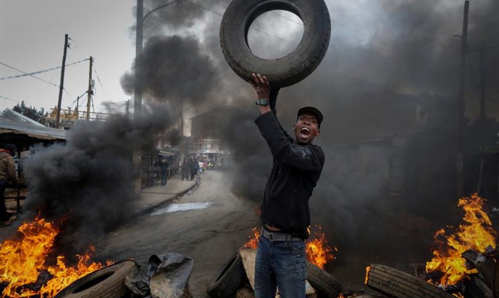 Vista de un hombre junto a una barricada con neumáticos quemados en el suburbio de Kibera, Nairobi, Kenia durante una nueva jornada de protestas en todo el país para exigir la dimisión de la autoridad electoral que supervisará las elecciones de 2017. EFE/