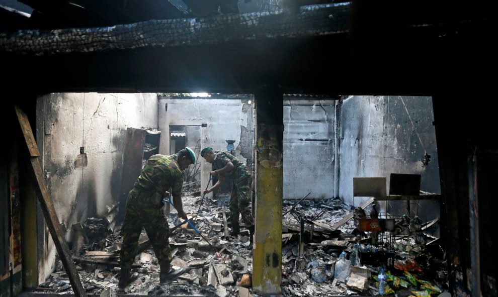 El grupo de trabajo especial de Sri Lanka (STF) limpia la destrucción causada por unas bombas en el interior de una tienda de armamento en Kosgama, Sri Lanka. REUTERS/Dinuka Liyanawatte