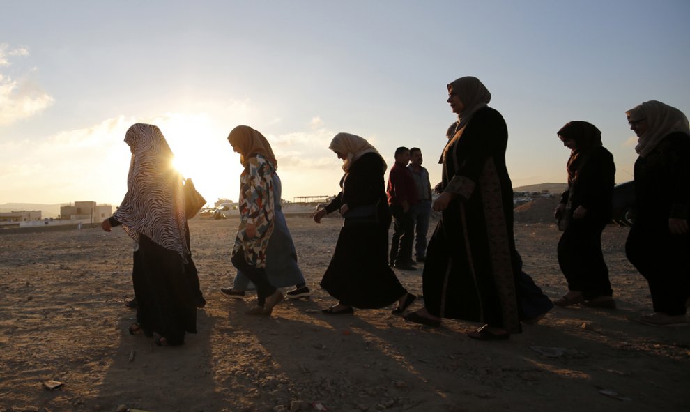 Mujeres palestinas caminan al amanecer hacia el puesto de control de Qalandia, un punto entre la ciudad cisjordana de Ramala y Jerusalén, tras el anuncio del primer ministro israelí, Benjamin Netanyahu, de una serie de medidas de castigo y disuasión contr