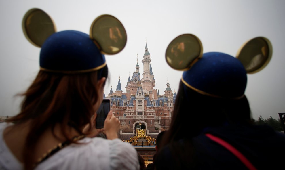 Dos chicas con un gorro de Mickey Mouse haciendo fotos de la gala de inauguración del parque temático