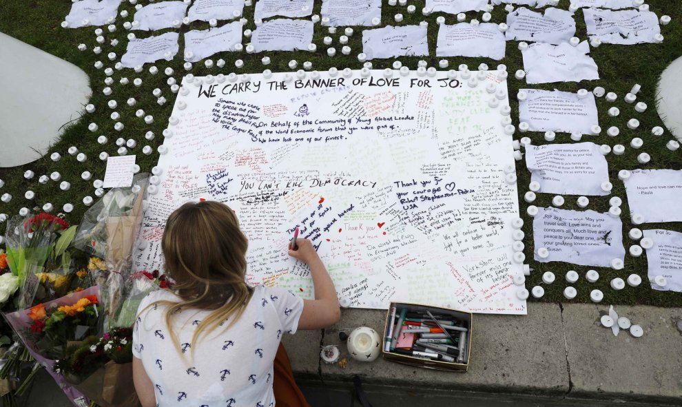 Una chica escribe un mensaje de apoyo en una placa en la plaza del Parlamento, en Londres