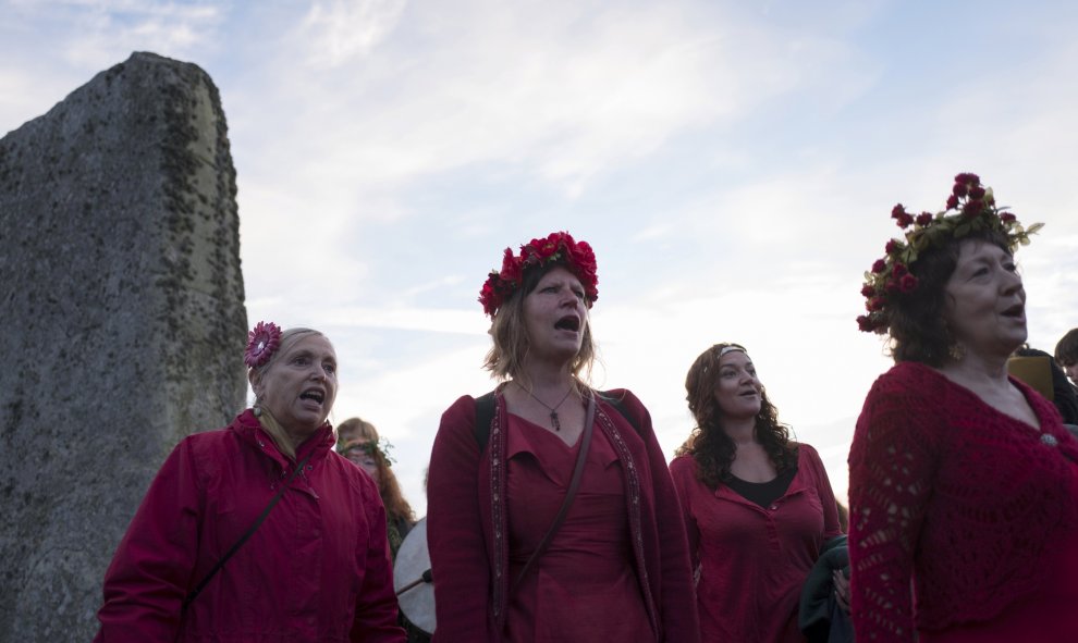 Varias mujeres vestidas de rojo cantando ante el monumento de Stonehenge