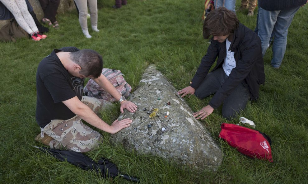 Dos hombres rezando ante una de las piedras de Stonehenge durante el solsticio, en Reino Unido