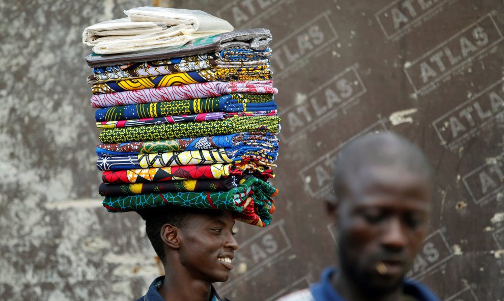 Un hombre vende telas sin coser conocidas localmente como "Ankara " camina en Lagos, Nigeria. REUTERS / Akintunde Akinleye