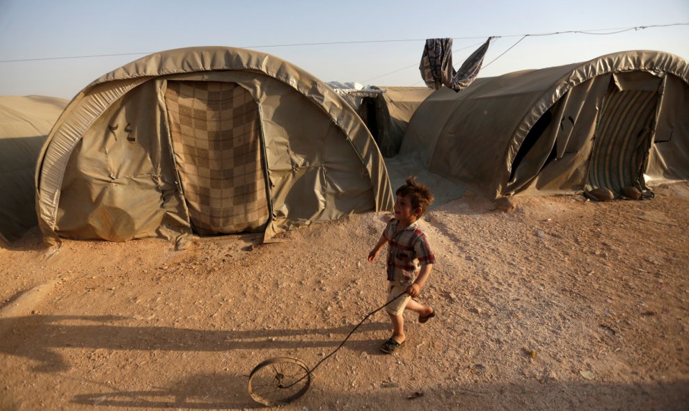 Un niño sirio refugiado juega con una rueda en el campo de Jrzinaz, en la parte sur de Idlib, Siria. REUTERS / Khalil Ashawi