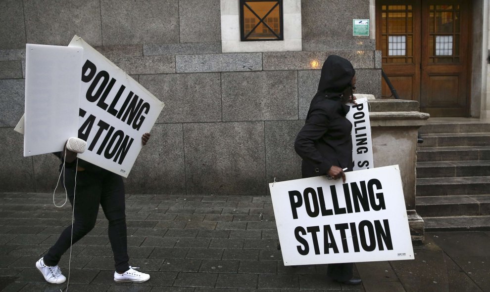 Los trabajadores para el referéndum llevando carteles que anuncian "punto de votación" en Londres
