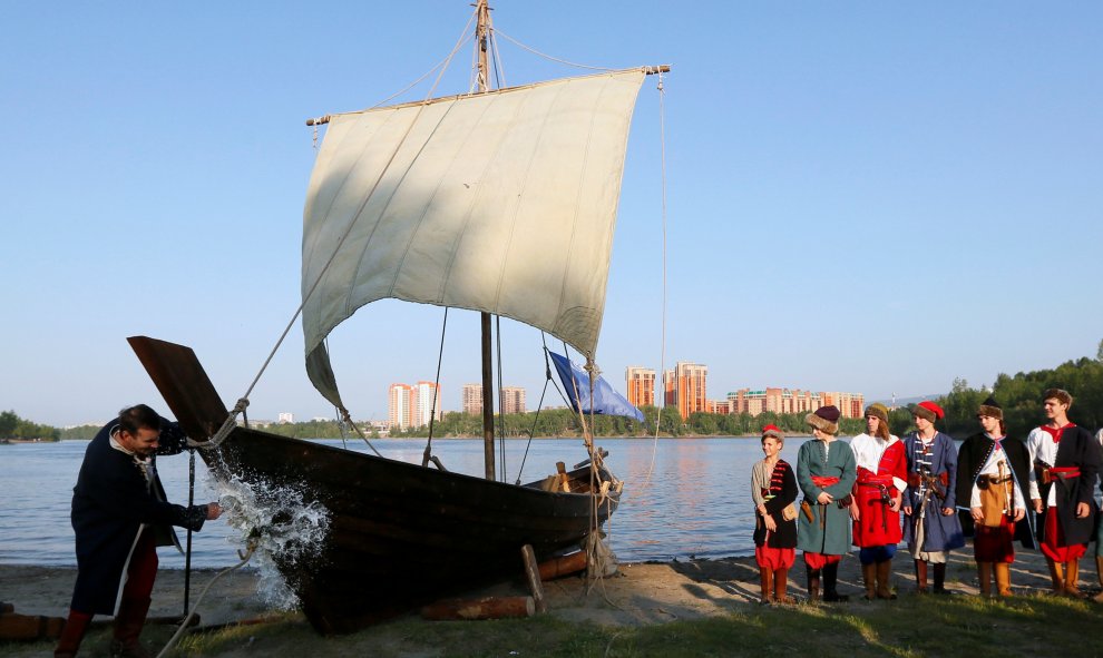 Un hombre rompe una botella de vino espumoso sobre el casco de una réplica de un antiguo barco velero ruso  durante la ceremonia de lanzamiento en una orilla del río Yenisei en Krasnoyarsk. REUTERS/Ilya Naymushin-