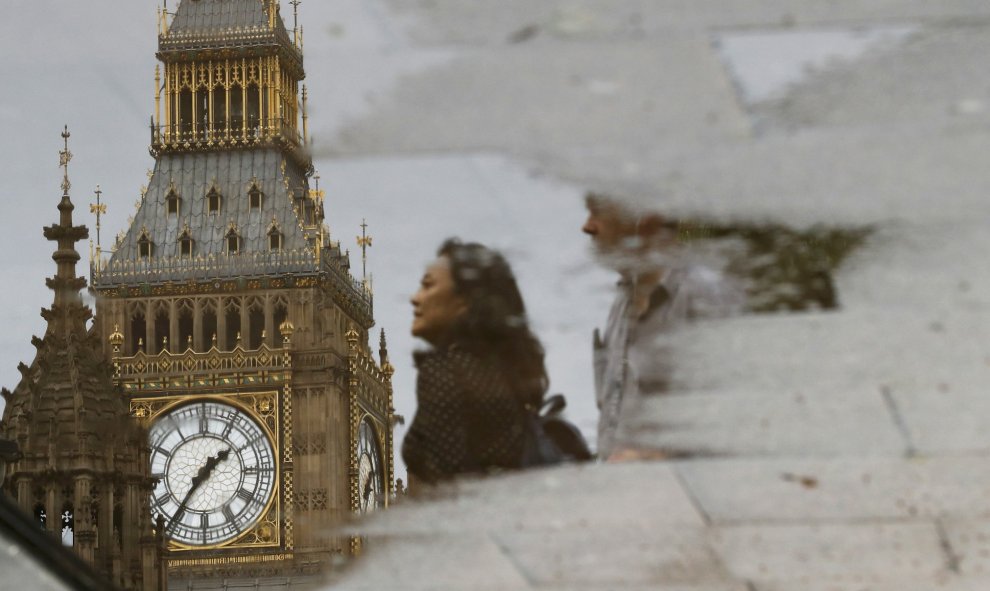 Personas reflejadas en un charco caminando junto al Parlamento londinense. REUTERS / Stefan Wermuth