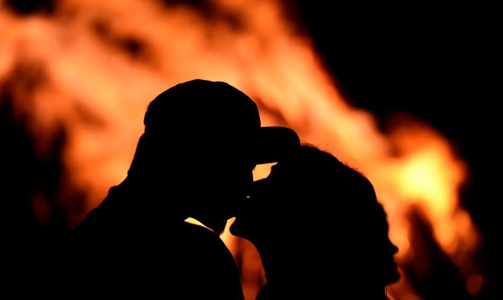 Una pareja se besa delante de una hoguera durante la tradicional noche de San Juan en Gijó. REUTERS / Eloy Alonso