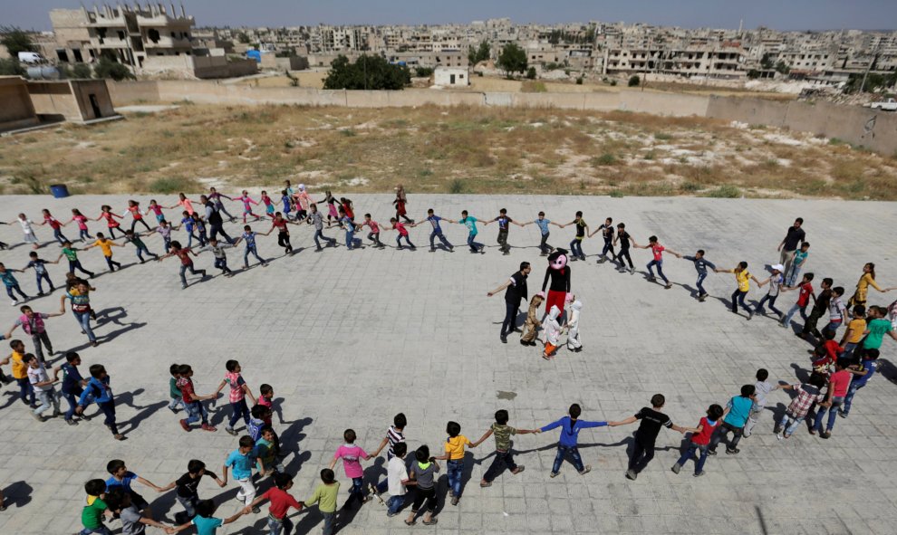 Los pequeños estudiantes forman un círculo para jugar y celebrar el último día de clase por la llegada del verano, en la ciudad de Maaret al-Numan, provincia de Idlib, Siria. REUTERS/Khalil Ashawi