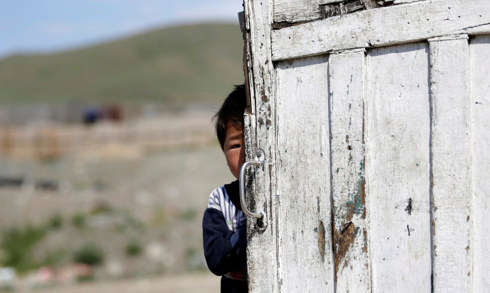 Un niño de cinco año se esconde tras una puerta en un pueblo de Mongolia. REUTERS/Jason Lee