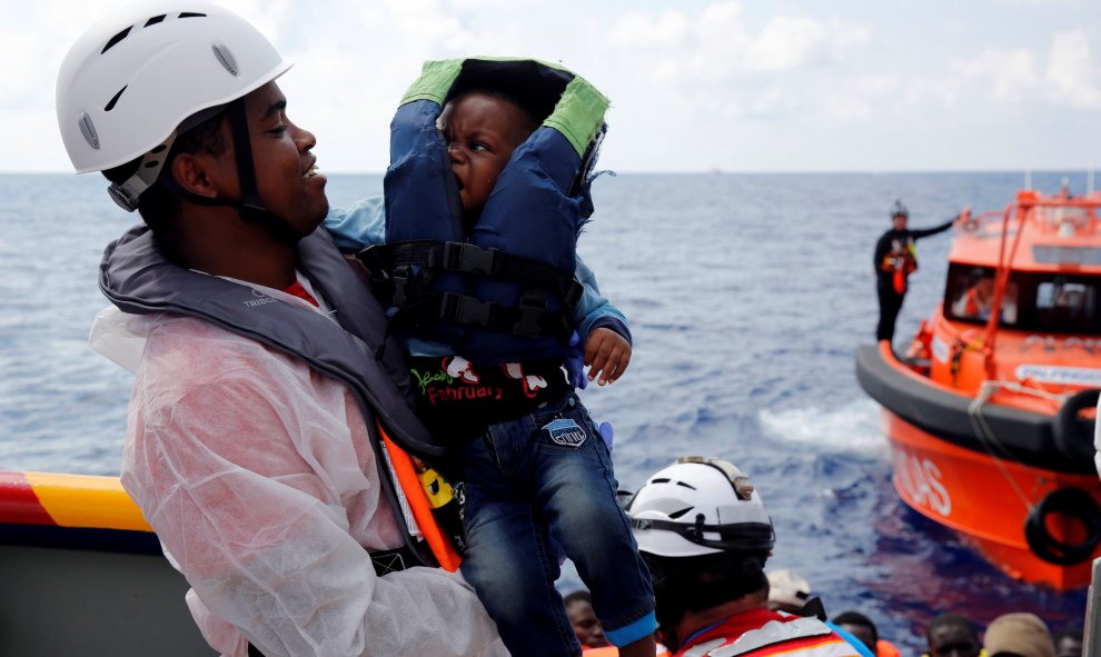 Un mediador cultural del italiano ONG EMERGENCIA lleva un bebé migrante a bordo del barco de rescate para inmigrantes Aid Station Marino ( MOEA ).-REUTERS / Darrin Zammit