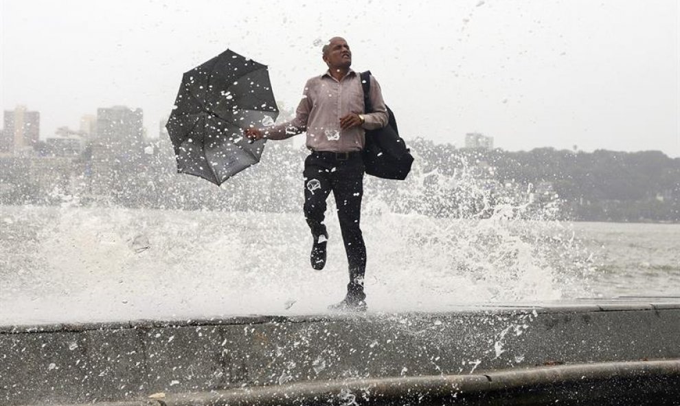 Una ola golpea a un indio durante la marea alta en el paseo marítimo de Bombay, India. El ochenta por ciento de las precipitaciones totales en la India se recogen durante el paso del monzón, de junio a septiembre. EFE/Divyakant Solanki