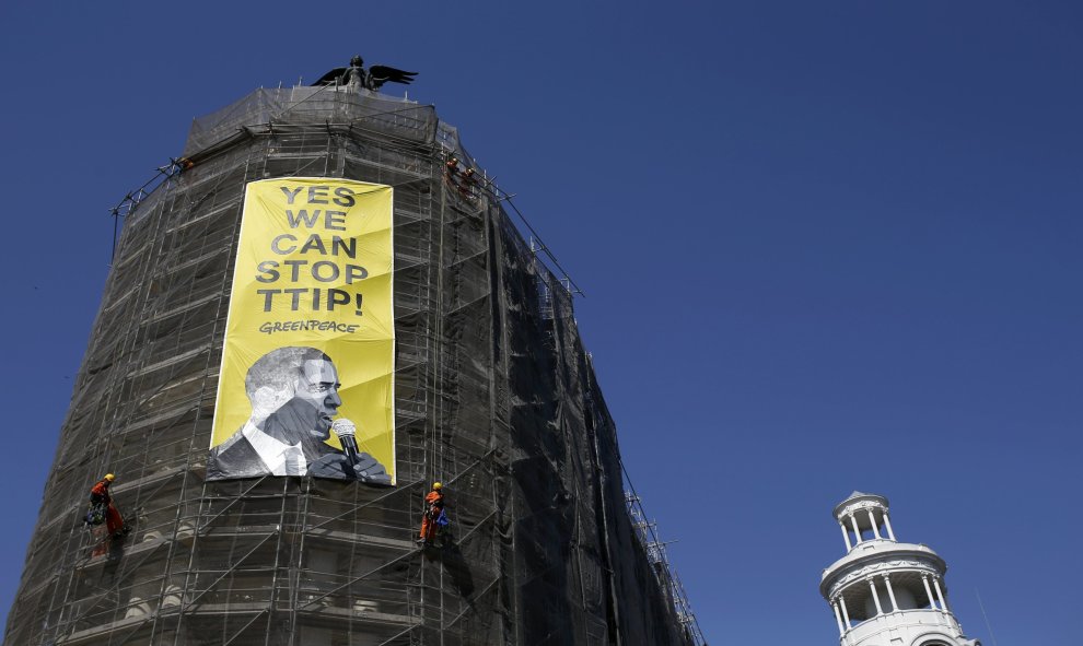 Activistas de Greenpeace cuelgan una pancarta con la imagen del presidente Barack Obama en la que se puede leer "Sí podemos parar el TTIP", en el edificio Metrópolis de la Gran Vía la calle en Madrid. REUTERS/Javier Barbancho