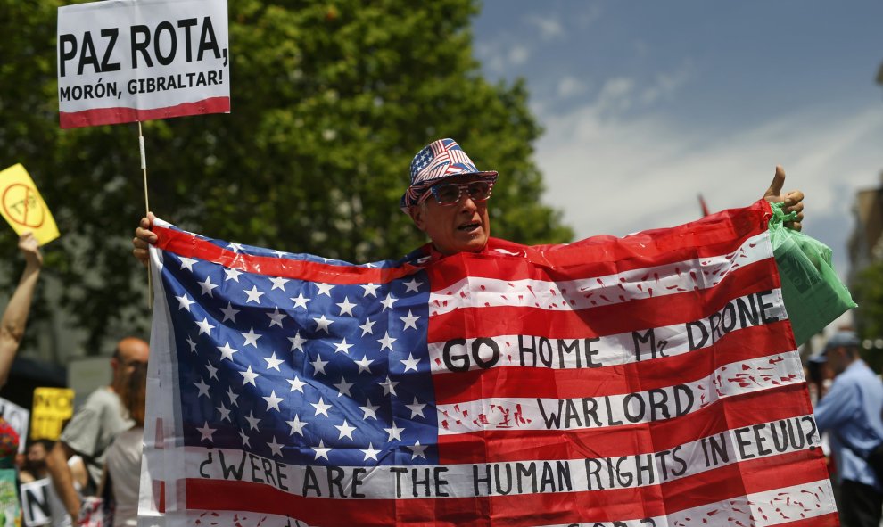 Un manifestante sostiene una bandera estadounidense con consignas durante una manifestación contra la visita del presidente Barack Obama en Madrid. REUTERS/Javier Barbancho