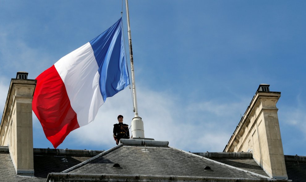 Un miembro de la Guardia Republicana tras bajar la bandera nacional francesa a media asta en el Palacio del Elíseo en París.- REUTERS / Philippe Wojazer
