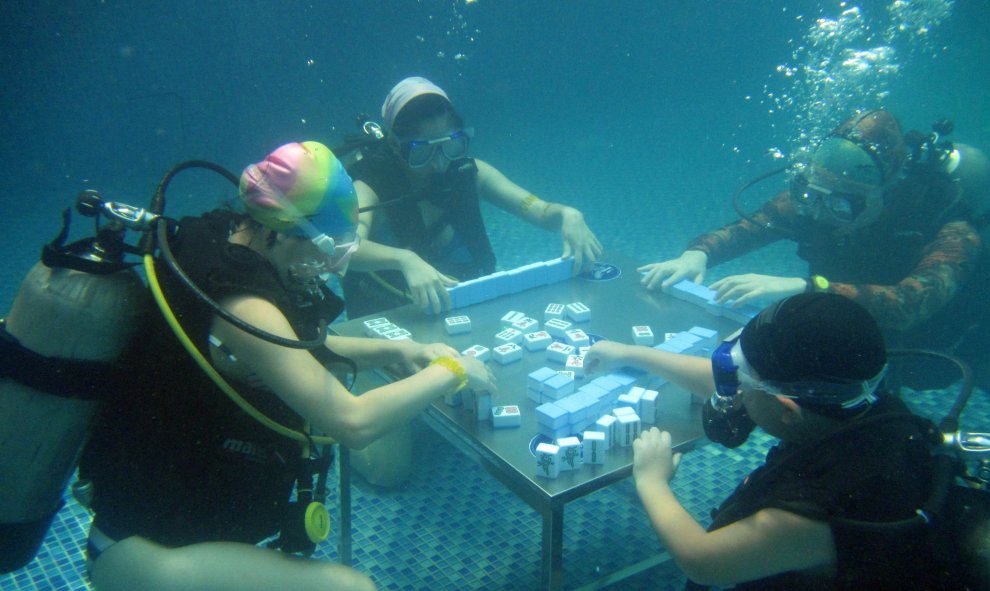 En china, varias personas juegan al "mahjong" en una piscina para soportar las sofocantes temperaturas del país, en Chongqing