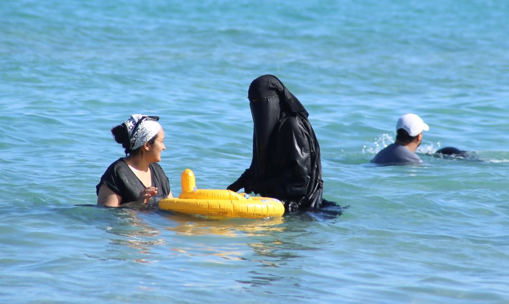 Una mujer se baña con un "niqab" en una playa de Túnez, para resistir el calor que sufre el país/REUTERS