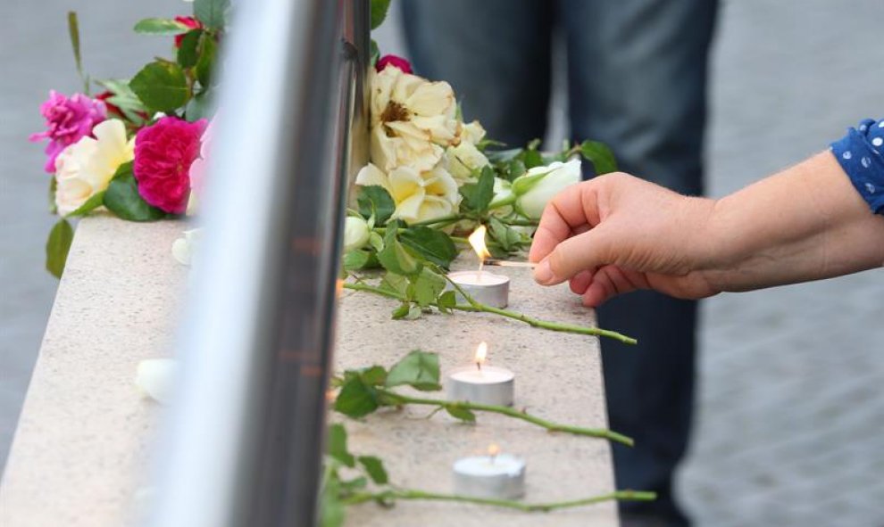 Una mujer enciende una vela en homenaje a las víctimas a la entrada del centro comercial donde se produjo el ataque. - EFE