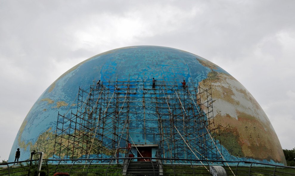 Un grupo de rabajadores elimina los andamios de una réplica del planeta tierra después de las reparaciones de la Ciudad de la Ciencia en Ahmedabad, India. REUTERS/Amit Dave
