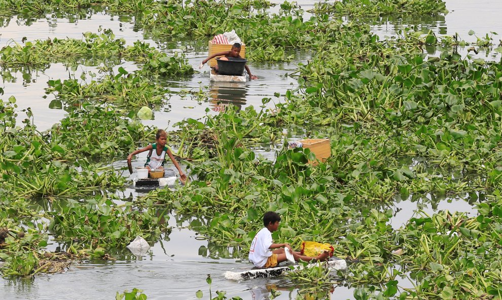 Niños filipinos atraviesan un río contaminado con barcas hechas por ellos mismos para recolectar elementos reutilizables en Manila, Filipinas/REUTERS