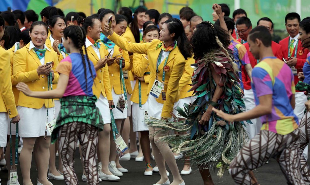 Deportistas chinas se hacen selfies con bailarinas durante su recepción en la Villa Olímpica. /REUTERS