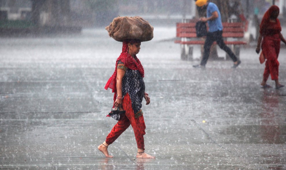 Una mujer lleva un saco fuera de un mercado durante las fuertes lluvias en Chandigarh, India. REUTERS/Ajay Verma