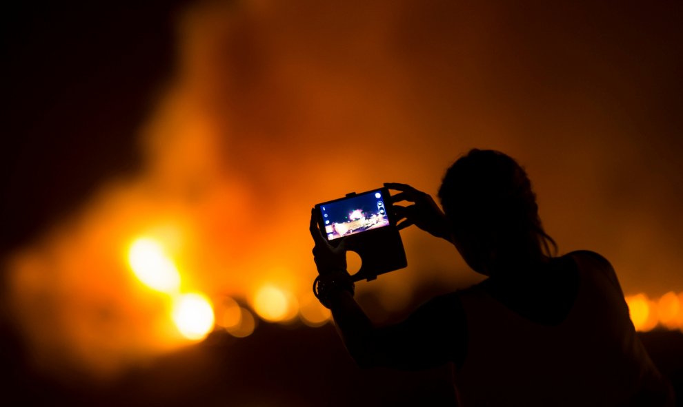 Una mujer graba con u móvil cómo el incendio arde sin control en Las Manchas, al suroeste de la isla de La Palma. REUTERS/Borja Suarez