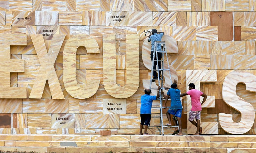 Un grupo de trabajadores coloca las letras de un anuncio para poner la palabra  "EXCUSE" (excusa) en Colombo, Sri Lanka. REUTERS/Dinuka Liyanawatte