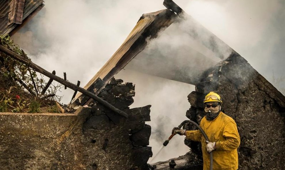 Un bombero refrescan los rescoldos tras incendiarse una casa en Fuchal, isla de Madeira (Portugal). Los tres fallecidos en los incendios que azotan Funchal, la capital del archipiélago luso de Madeira, son de la misma familia y hay un total de 300 heridos