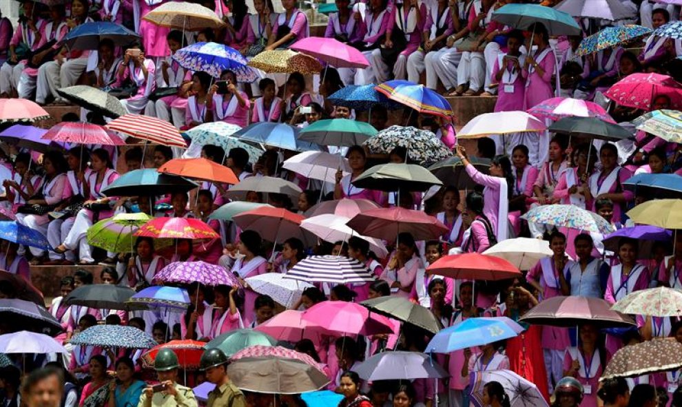 Un grupo de escolares esperan bajo los paraguas la llegada de la gimnasta india Dipa Karmakar en la ciudad de Agartala, capital del estado de Tripura, India. EFE