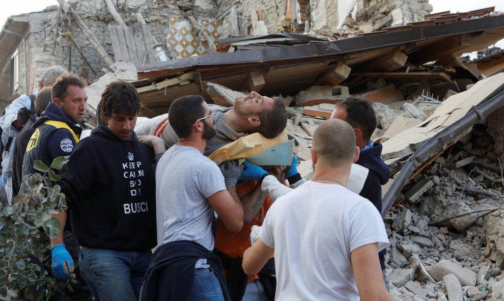 Un hombre, rescatado de entre los escombros, es llevado a hombros por varios voluntarios/REUTERS
