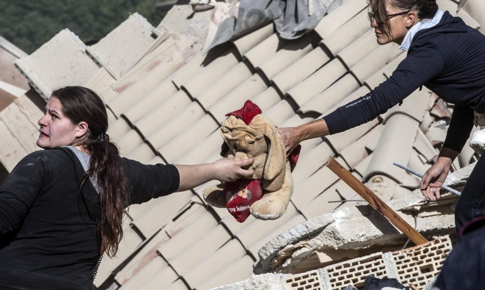 Dos mujeres de los equipos de rescate sostienen un peluche entre los escombros de Amatrice, tras el terremoto en el centro de Italia. EFE/Massimo Percossi