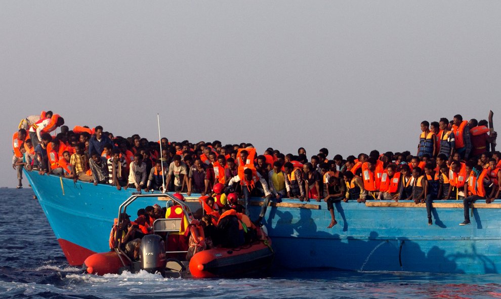 Un barco de rescate de la ONG española Proactiva se acerca a una patera de madera abarrotada de inmigrantes procedentes de Eritrea, frente a la costa de Libia en el Mar Mediterráneo. REUTERS/Giorgos Moutafis