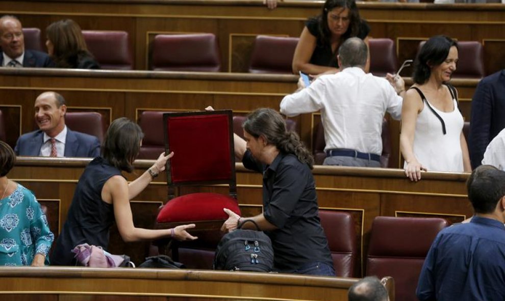 Los dirigentes de Podemos Pablo Iglesias (d) e Irene Montero (i) se acomodan en el hemiciclo poco antes del comienzo de la primera jornada del debate de investidura a la que se someterá el presidente del Gobierno en funciones, Mariano Rajoy. EFE/Juan Carl